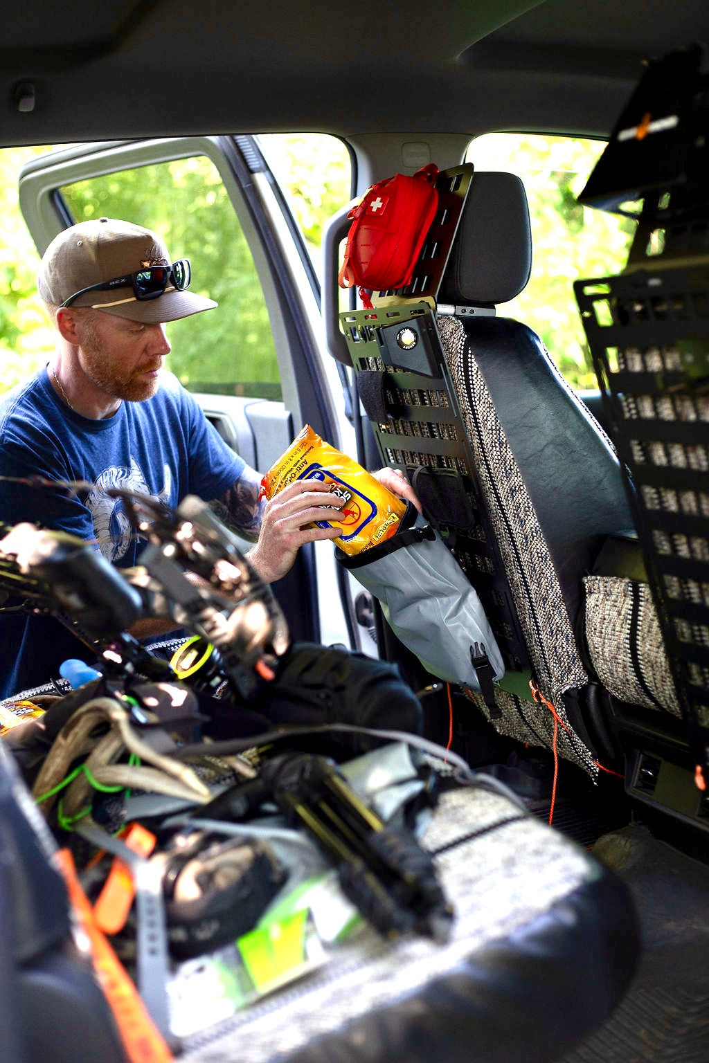 Man loading hunting gear onto a Gear Anchor MOLLE panel, organizing equipment for the season.