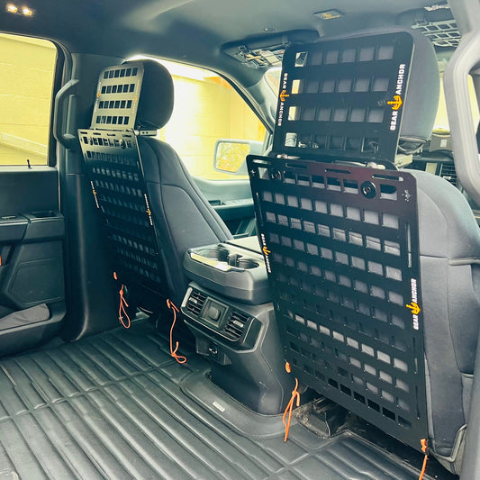 Rear seat of a pickup truck featuring two Gear Anchor universal MOLLE panel systems mounted behind the headrests for organized hunting gear storage.